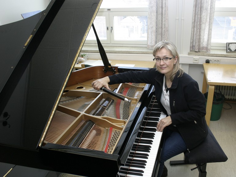 The CEO Päivi Heinilä tuning a piano.